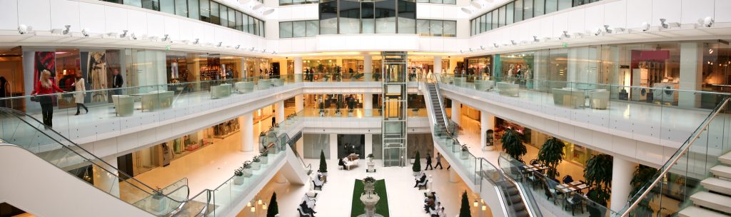 Inside of a modern shopping mall showing three floors of shopping retail.