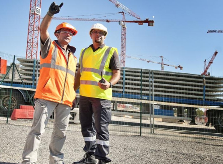 Two men at a construction site in high vis vest, one is holding a Hytera portable radio