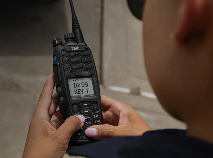 User holding a black Tait P25 TP9600 portable radio
