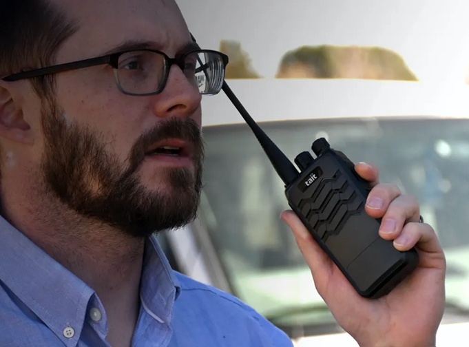 Man holds a black Tait TP2 DMR portable radio